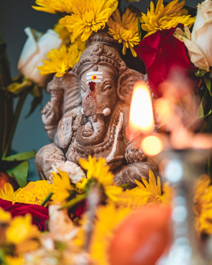 gallery-5 A detailed Ganesha statue amidst bright yellow and red flowers, symbolizing spirituality and peace.